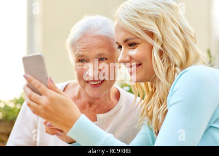 Fille et mère senior avec piscine smartphone Banque D'Images