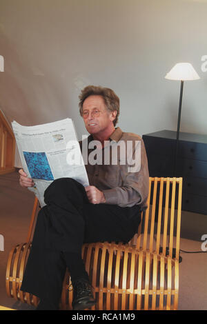 Mann mittleren modifie liest Zeitung auf einem Stuhl | homme d'âge moyen est de lire le journal sur une chaise Banque D'Images
