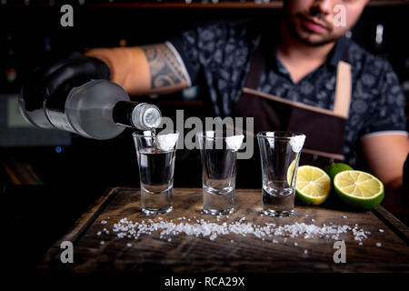 Barman pouring disque esprit dans de petits verres comme les coups de tequila ou de boisson forte Banque D'Images