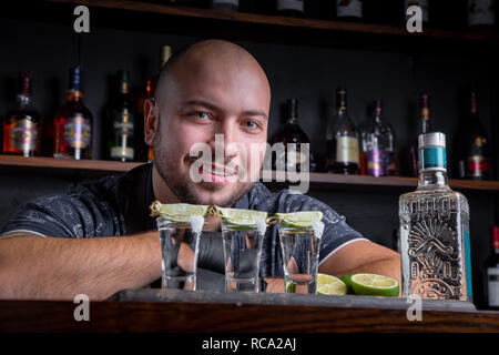 Barman pouring disque esprit dans de petits verres comme les coups de tequila ou de boisson forte Banque D'Images