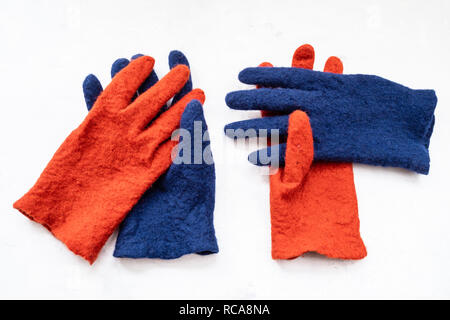 Nouveau feutre fait main gants orange et bleu sur conseil de béton gris Banque D'Images