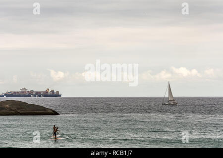 2019, janvier. Rio de Janeiro, Brésil. Grand navire, bateau à voile et Stand Up Paddle surfer sur la plage de Copacabana. Banque D'Images