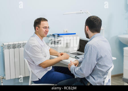 Médecin homme discutant avec des rapports patient à 24 in medical office Banque D'Images