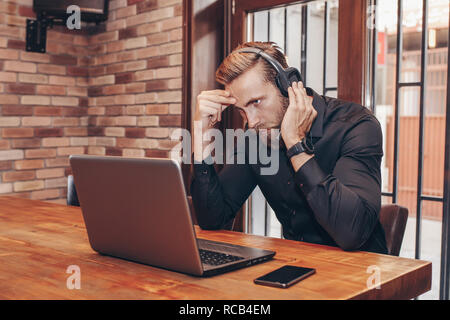 Businessman working barbu inquiet essayant de résoudre des problèmes en ligne avec un ordinateur portable au bureau - Image Banque D'Images