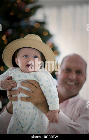 Portrait d'un jeune bébé portant un chapeau alors qu'eu lieu en altitude par son père sourire. Banque D'Images