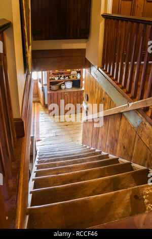 Vue sur l'escalier en bois de pin depuis l'étage supérieur menant à l'entrée avec buffet en bois à l'intérieur d'une ancienne maison en pierre de champ de 1835. Banque D'Images