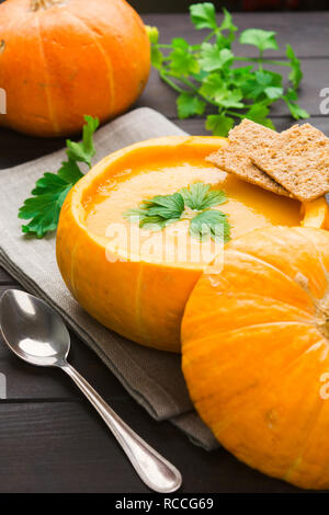 Soupe au potiron avec des croûtons et le persil dans la citrouille naturelle, vertical shot Banque D'Images