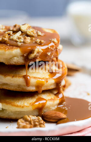 Pile de macro avec des délicieuses crêpes lait condensé, caramel et des écrous sur la plaque blanche à l'arrière-plan clair. Fond doux romantique Banque D'Images