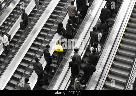 Homme porte sac jaune escalator ascendant Banque D'Images