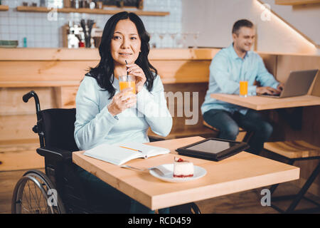 Dame réfléchie boire du jus dans un café Banque D'Images