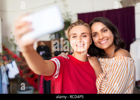 Amies en tenant au magasin de vêtements de selfies Banque D'Images