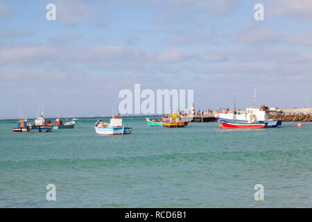 Bateaux de pêche colorés en Struisbaai Harbour, l'Agulhas, Western Cape, Afrique du Sud avec les touristes sur le quai près du phare Banque D'Images