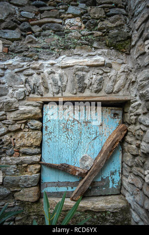 Très petit espace fenêtre coupé en une maison en pierre recouvert de vieux bois et de l'obturateur bloqué, en France Banque D'Images
