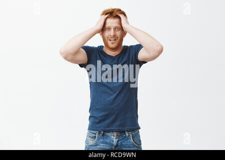 Guy commence à paniquer manque de temps pour rédiger les articles. Nerveux et anxieux gingembre attrayant homme avec barbe, toucher les cheveux, regardant choqués et inquiets à l'appareil photo, stucking en situation problématique Banque D'Images