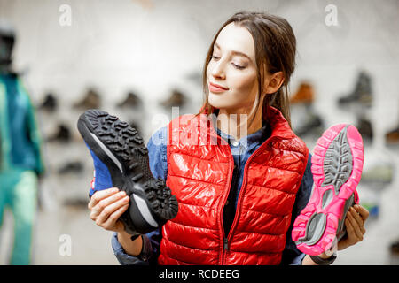 Jeune femme choisir chaussures de trail pour la randonnée dans le magasin de sport moderne Banque D'Images