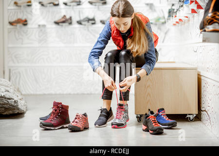 Femme essayant des chaussures pour la randonnée dans la séance d'essayage du magasin de sport moderne Banque D'Images