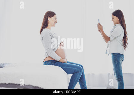 Girl taking photo agréable de sa mère enceinte Banque D'Images