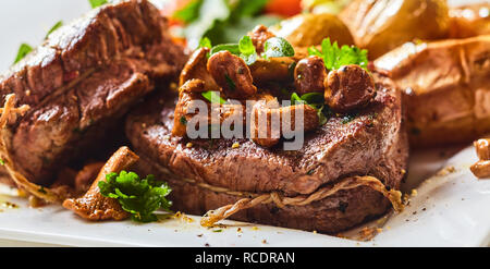 Offres d'épaisseur maigre filet de boeuf rôti rares assaisonné et mariné médaillons et servi avec des champignons et du persil frais dans une vue en gros plan Banque D'Images