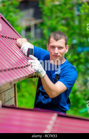 Portrait d'un homme vertical avec un marteau de réparer le toit de la maison, des prises de vue en extérieur Banque D'Images