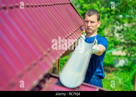 Réparateur avec un tuyau de vidange de l'eau de la toiture, réparation accueil Banque D'Images