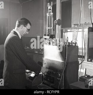 1950s, historique, à l'intérieur d'un laboratoire de recherche scientifique, un scientifique mâle dans une combinaison à rayures à l'aide d'équipements d'essai de l'époque, Leeds University, Leeds, Angleterre, Royaume-Uni Banque D'Images