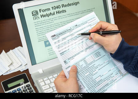 Refonte 1040 Conseils utiles sur un moniteur portable, la main de l'homme examen formulaire 1040. Banque D'Images