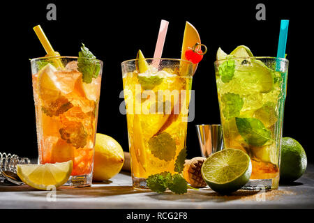Un assortiment de cocktails de fruits frais mélangé avec de l'alcool et de feuilles de menthe et servi sur glace dans des grands verres avec des ingrédients, y compris le citron, lime et kiwif Banque D'Images