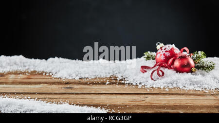 Carte d'hiver avec deux boules de Noël rouges et de branches de sapin sur la neige sur une planche en bois rustique sur fond noir pour copy space Banque D'Images