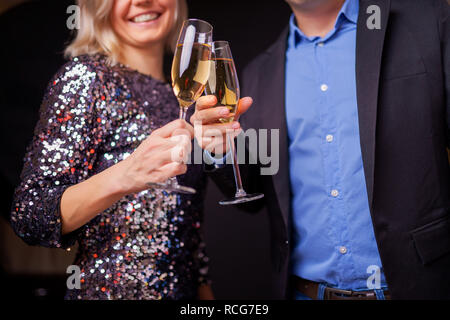 Photo de l'heureux couple avec verres de champagne en studio Banque D'Images