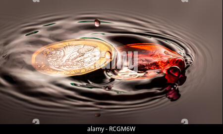 Couleur rouge goutte d'eau éclaboussant sur un Euro et sterling pièce brexit étang anglais Banque D'Images
