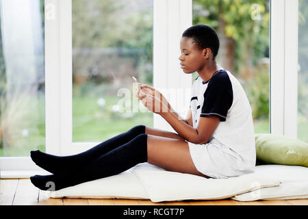 Fille ethnique à la détente à son téléphone Banque D'Images