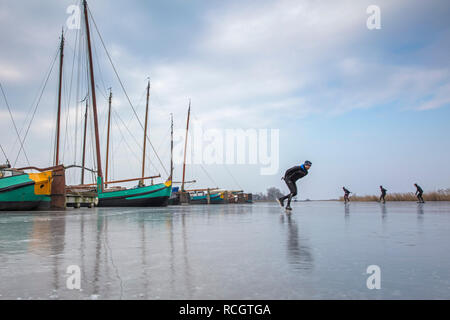 Les Pays-Bas, Sloten, patinage sur glace. Contexte du fret traditionnel des bateaux à voile. L'hiver. Banque D'Images