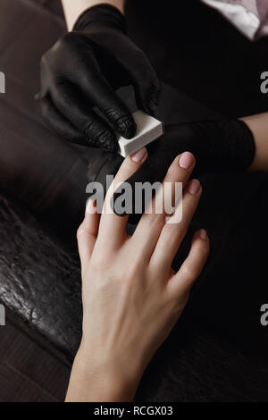 Manucure avec des gants noirs, une unité de polissage, un buff qui gère les ongles. Se prépare pour l'extension de l'ongle. Des installations de spa. Salle de manucure. Banque D'Images