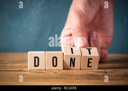 Retourne la main deux cubes avec des lettres, en changeant le mot 'do it' dans 'DONE' sur la surface en bois Banque D'Images