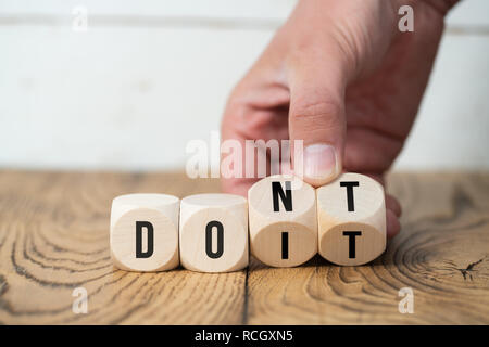 Retourne la main deux cubes avec des lettres, en changeant le mot 'ne' dans 'do it' sur la surface en bois Banque D'Images