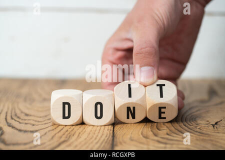 Retourne la main deux cubes avec des lettres, en changeant le mot 'ne' dans 'do it' sur la surface en bois Banque D'Images