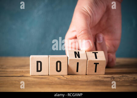 Retourne la main deux cubes avec des lettres, en changeant le mot 'ne' dans 'do it' sur la surface en bois Banque D'Images