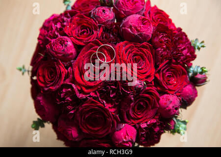 Une paire de bagues de mariage sur un bouquet de roses rouges et de pivoines, Close up shot Banque D'Images