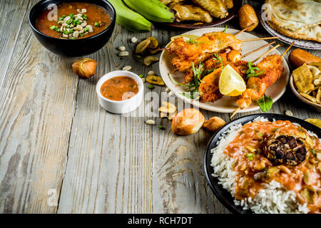 Concept alimentaire en Afrique de l'Ouest. Wset traditionnels mets africains assortiment - soupe d'arachides, de riz jollof, ailes de poulet grillées à sec, les plantains, bananes frites Banque D'Images