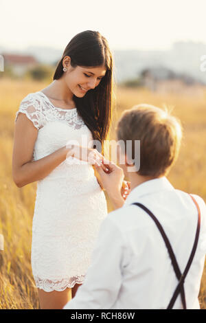Jeune homme à la bague de fiançailles faire proposition à sa chère petite amie à l'extérieur. Bague de fiançailles de mettre des hommes sur la femme, à l'extérieur, elle sourit Banque D'Images