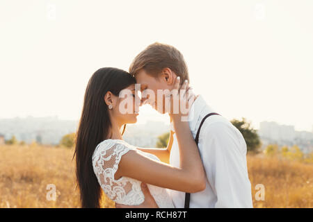 Couple aimant habillé en blanc, prêt à baiser en plein air avec les yeux fermés, toucher doux, l'autre avec un paysage flou en arrière-plan, golden gr Banque D'Images