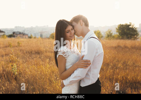 Couple aimant habillé en blanc à l'extérieur, s'embrasser, toucher doux les uns les autres avec un beau paysage en arrière-plan, l'herbe d'or - Concept de pe Banque D'Images