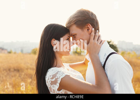 Couple aimant habillé en blanc à l'extérieur, s'embrasser, toucher doux les uns les autres avec un beau paysage en arrière-plan, l'herbe d'or - Concept de pe Banque D'Images