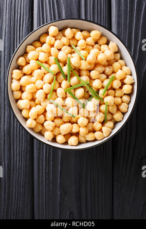 Pois chiches bio frais bouilli avec des oignons verts close-up dans un bol sur la table. Haut Vertical Vue de dessus Banque D'Images