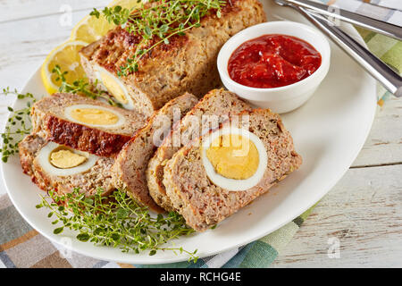 Viande farcies avec oeuf dur servi avec une sauce tomate et des rondelles de citron sur une plaque blanche sur une vieille table en bois, vue horizontale à partir de ci-dessus, Banque D'Images