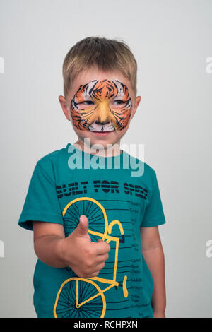 Charmant petit garçon avec un visage de tigre. aqua maquillage face painting. Banque D'Images