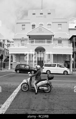 Hamilton, Bermudes - Mars 20, 2016 : femme en scooter sur rue. Femme sur un cyclomoteur sur paysage de rue. Rapide et gratuit femme. En transport pour femme confiante. Le voyage. Banque D'Images