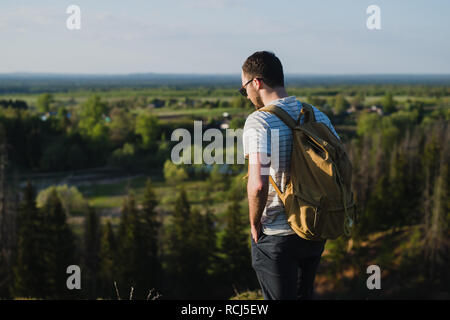 L'homme sur le fond de la nature avec un sac à dos sur son dos. L'homme cherche dans la distance Banque D'Images