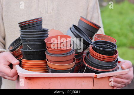 Jardinier vide noir et rouge des plantes en plastique pots dans un bol en plastique, UK jardin. Jardinage en plastique Banque D'Images