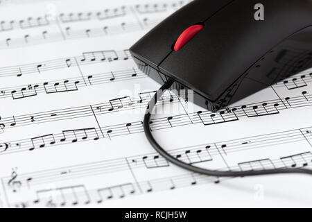 Souris d'ordinateur sur une feuille avec des notes de musique, close-up avec focus sélectif. Le concept de la numérisation de la musique Banque D'Images